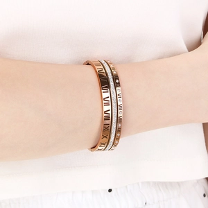 Close-up of rose gold hollow roman numeral bangles set with zircons on a model wrist