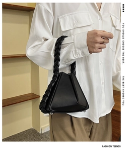 Close-up of black geometric triangle handbag with woven handle and protective metal feet