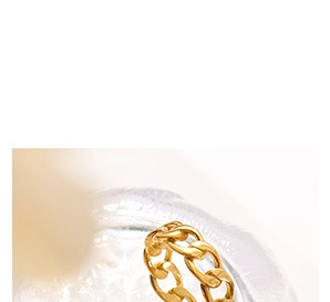 Macro shot of gold-plated stainless steel chain ring on a textured crystal surface