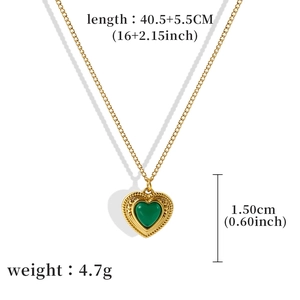 Vintage gold necklace with green heart gemstone pendant and engraved details on white background