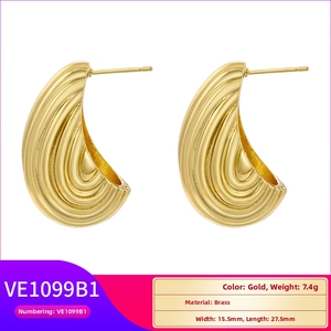 Detailed macro view of gold C-shaped brass earrings with textured wavy ripple surface