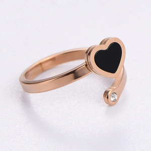 Rose gold heart ring with black enamel and sparkling zircon on a light grey texture