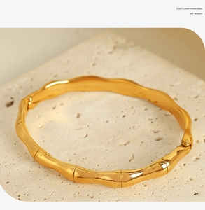 Macro shot of gold-plated bamboo joint bangle on beige travertine stone texture