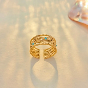 Detail of gold layered wave ring with blue rhinestones and star engravings