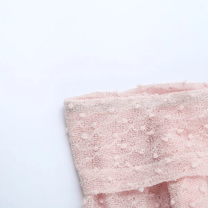 Détail du tissu tricoté rose avec texture 3D à pompons et maille dentelle sur une robe