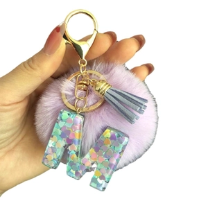 Porte-clés pompon violet avec pendentif lettre M en résine et fermoir doré en main