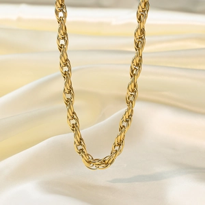 Detail of a chunky gold twisted rope chain necklace on elegant white silk background