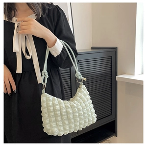 Primo piano della borsa trapuntata bianca con tracolla verde chiaro su modella in nero