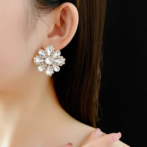 Close-up of elegant flower earrings with sparkling crystals worn by a model in a side view