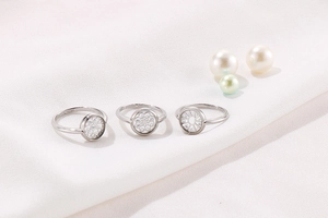 Dettaglio di anelli geometrici in argento con zirconi e motivi floreali traforati
