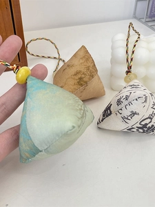 Three handmade fabric zongzi charms with traditional patterns and colorful braided cords