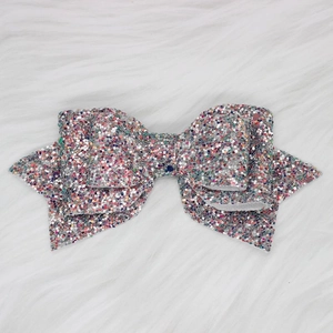 Close-up of colorful glitter bow straw toppers on white faux fur background decoration