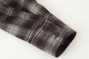 Close-up of adjustable double-button cuffs on a grey and brown plaid flannel shirt