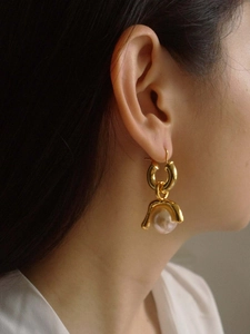 Macro shot of detachable vintage gold earrings with natural pink pearls on model