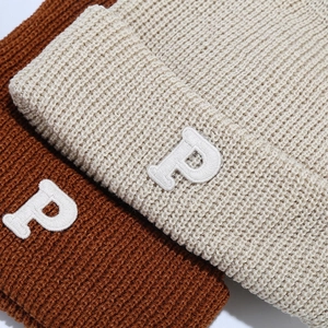 Detail of waffle knit beanies in caramel and beige featuring white P letter embroidery