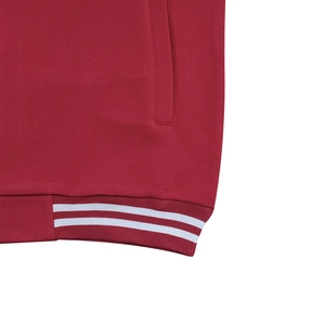 Détail de l'ourlet de la veste de sport rouge avec rayures blanches et maille côtelée