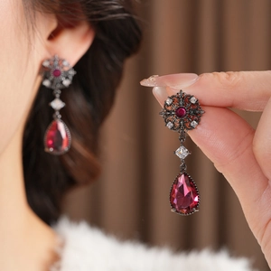 Détail macro de boucles d'oreilles fleurs ajourées avec pierre rouge et zircons