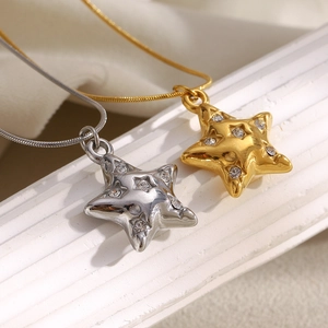 Detailed view of gold and silver star pendants with sparkling rhinestones on white fabric