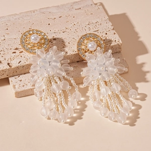 Détail de boucles d'oreilles pendantes avec strass, perles et pompons de perles