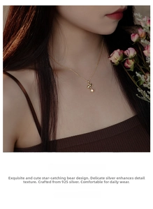 Detail of s925 silver golden teddy bear necklace on model with rose background