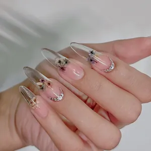 Detailed view of floral press-on nails featuring real dried flowers and silver rhinestones