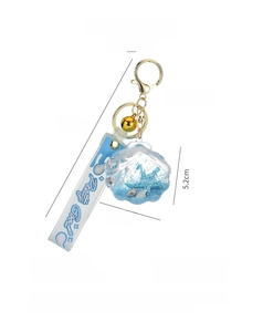 Detail of seashell acrylic oil keychain with blue fluid and golden bell attachment