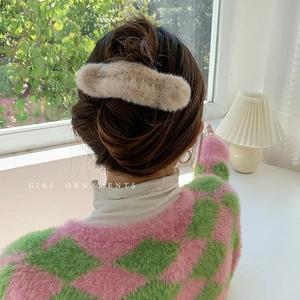 Plush khaki claw clip for elegant updo hairstyle on model in cozy home setting