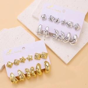 Chic gold and silver geometric earring set with stars and hoops on white stone background