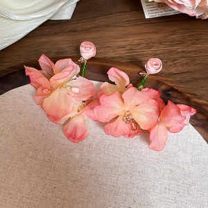 Macro view of pink fabric floral earrings with silk petals and green bead stems