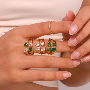 Close-up of gold plated rings with green heart and teardrop zircon on a model's hand