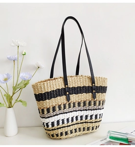 Detail view of woven straw tote bag texture with natural yellow and black stripes