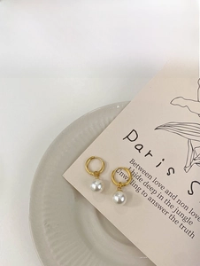 Detail of 18K gold titanium earrings with elegant pearl pendants on artistic background