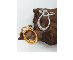 Detailed view of gold and silver knot rings with pavé zircon on natural wood
