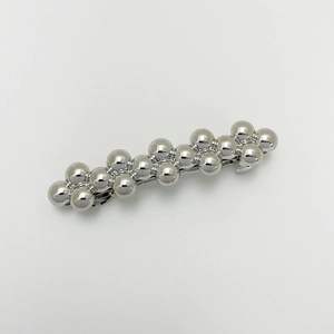 Detail of silver metallic hair clip with connected spherical beads in a punk style