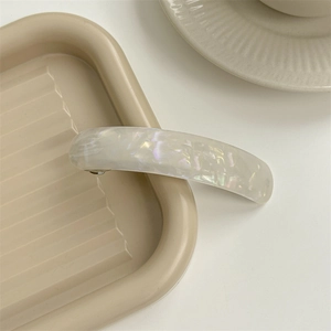 Macro view of a rectangular acetate spring hair clip with pearlescent marble texture