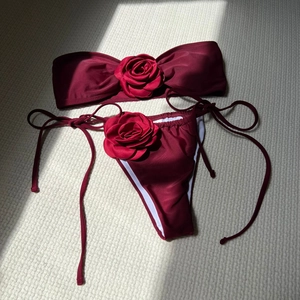 Detailed close-up of wine red bikini with 3D rose floral accents and side-tie bottom