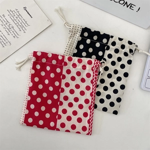 Macro view of polka dot cotton drawstring storage bags with vintage card on white surface