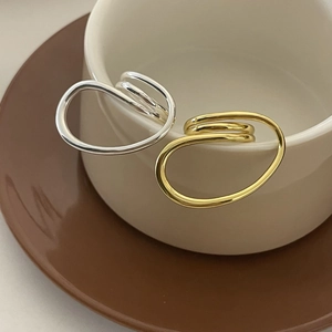 Close-up of gold and silver layered ear cuffs displayed on a white ceramic cup edge