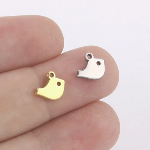 Minimalist gold and silver bird charms on fingertips for DIY jewelry making