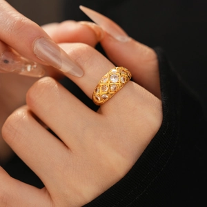 Macro shot of gold-plated lattice ring with sparkling cubic zirconia on model's finger
