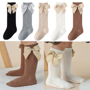 Detail of vintage hollow-knit baby knee-high socks with large decorative silk bows