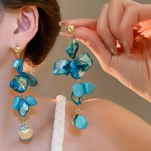 Close-up of blue irregular shell earrings with a golden shell pendant on model