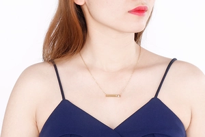 Macro shot of gold horizontal bar necklace with tiny heart cutout and zircon inlay