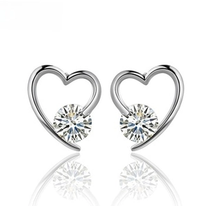 Macro detail of silver heart stud earrings featuring brilliant round-cut center stones