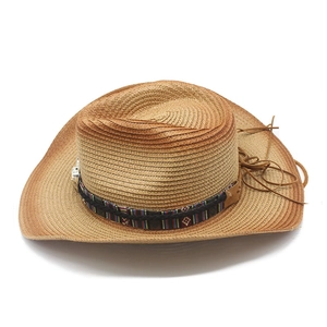 Détail d'un chapeau de paille de cowboy avec ruban brodé ethnique et cordon en cuir brun