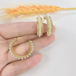 Detailed view of hand-held gold plated 18k pearl hoop earrings with vintage texture