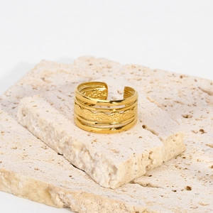Détail d'une bague dorée au motif de feuille tressée sur pierre naturelle montrant l'artisanat