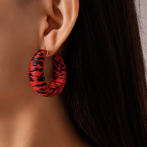 Detail shot of red and black leopard print C-shaped hoop earrings on a model