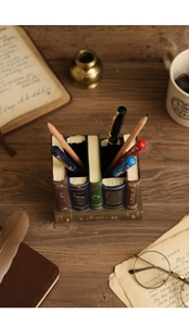 Macro view of vintage resin book-shaped pen holder with detailed spines and gold accents