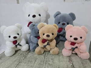 Detalle de varios ositos de peluche con rosas rojas y lazos de lunares sobre madera
